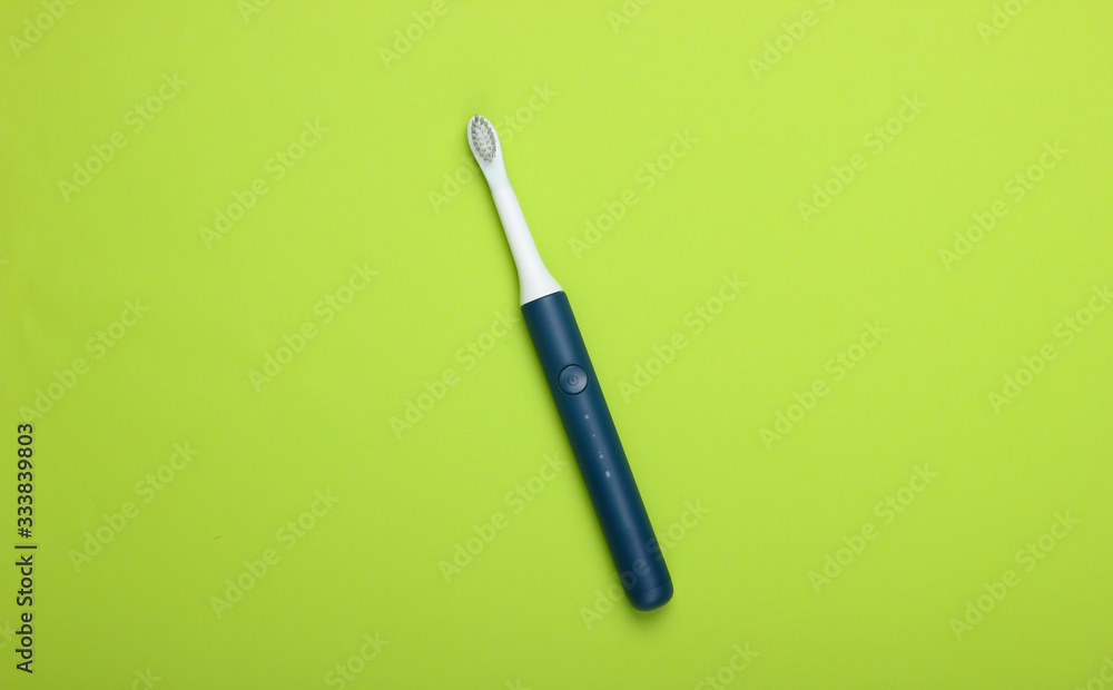 Modern electric toothbrush on green background. Top view. Teeth care. Minimalism Modern electric toothbrush on green background. Top view. Teeth care. Minimalism