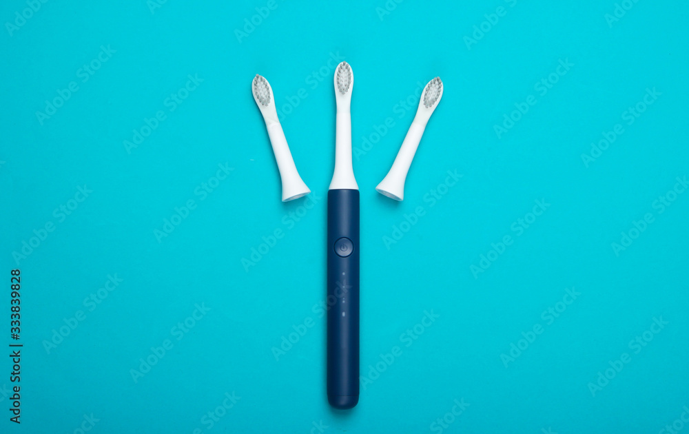 Teeth care. Modern electric toothbrush with nozzles on blue background. Top view. Minimalism Teeth care. Modern electric toothbrush with nozzles on blue background. Top view. Minimalism