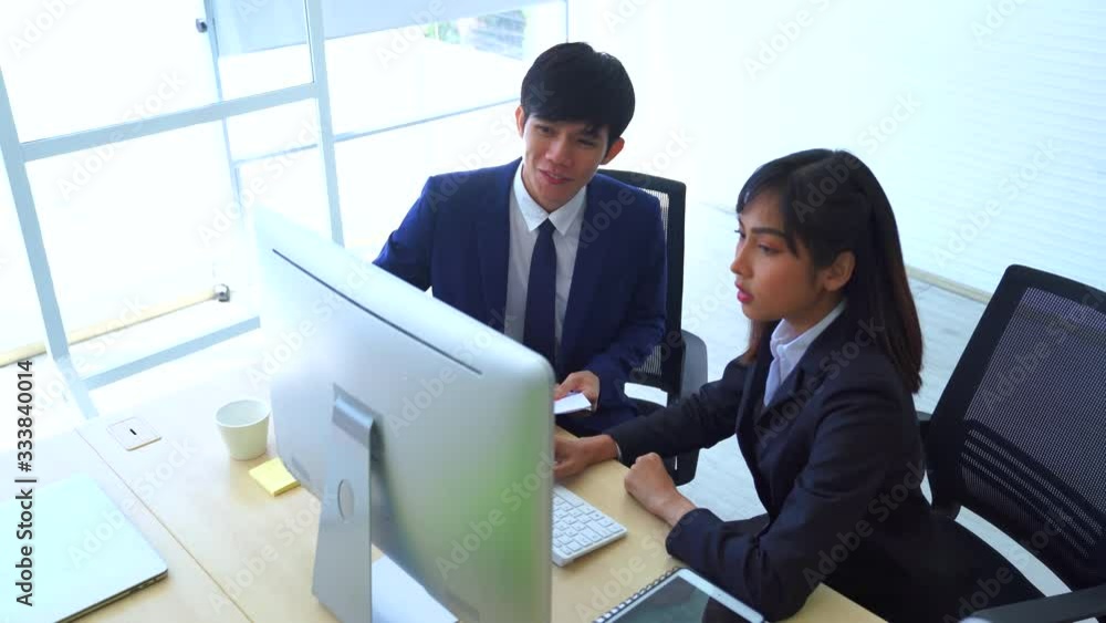 Asian female working with her co-worker on computer.