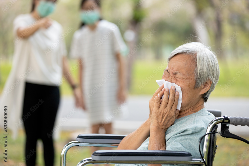 Sick asian senior woman has a runny nose,fever with sneezing on tissue,symptoms infection of flu,covid-19,Coronavirus pandemic,two people wearing a mask,avoid contact with patient,maintain distance Sick asian senior woman has a runny nose,fever with sneezing on tissue,symptoms infection of flu,covid-19,Coronavirus pandemic,two people wearing a mask,avoid contact with patient,maintain distance