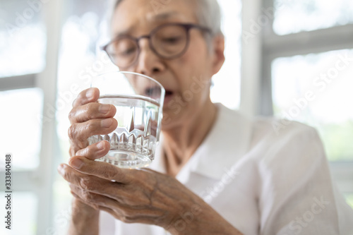 Senior woman holding glass of water,hand shaking while drinking water,elderly patient with hands tremor uncontrolled body tremors,symptom of essential tremor,parkinson's disease,neurological disorders photo