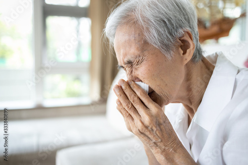 Sick asian senior woman blowing nose with tissue paper while runny nose,sneeze,elderly with sinusitis,sinus virus disease,infection symptom of flu,cold,fever,old people with respiratory problems