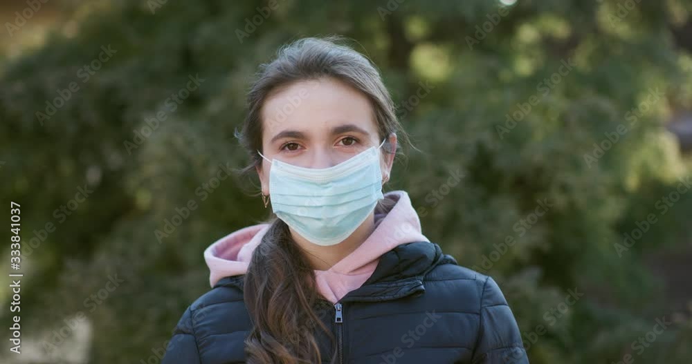 Attractive Girl Takes on Medical Mask. Breathes deeply and looking at camera on green background. Health care and medical concept Attractive Girl Takes on Medical Mask. Breathes deeply and looking at camera on green background. Health care and medical concept