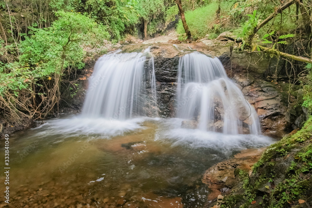 view of silky waterfall flowing on cliff rocks around with green forest background, Mae Pan Waterfall, Doi Inthanon National Park, Chiang Mai, northern of Thailand.