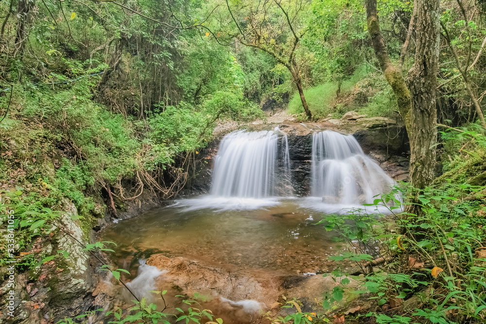 view of silky waterfall flowing on cliff rocks around with green forest background, Mae Pan Waterfall, Doi Inthanon National Park, Chiang Mai, northern of Thailand. view of silky waterfall flowing on cliff rocks around with green forest background, Mae Pan Waterfall, Doi Inthanon National Park, Chiang Mai, northern of Thailand.