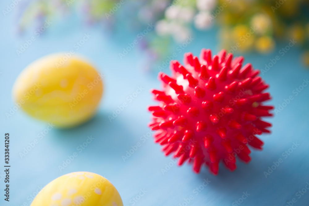 Virus model of Coronavirus disease COVID-19 with colorful easter eggs with flowers on a blue wooden table background