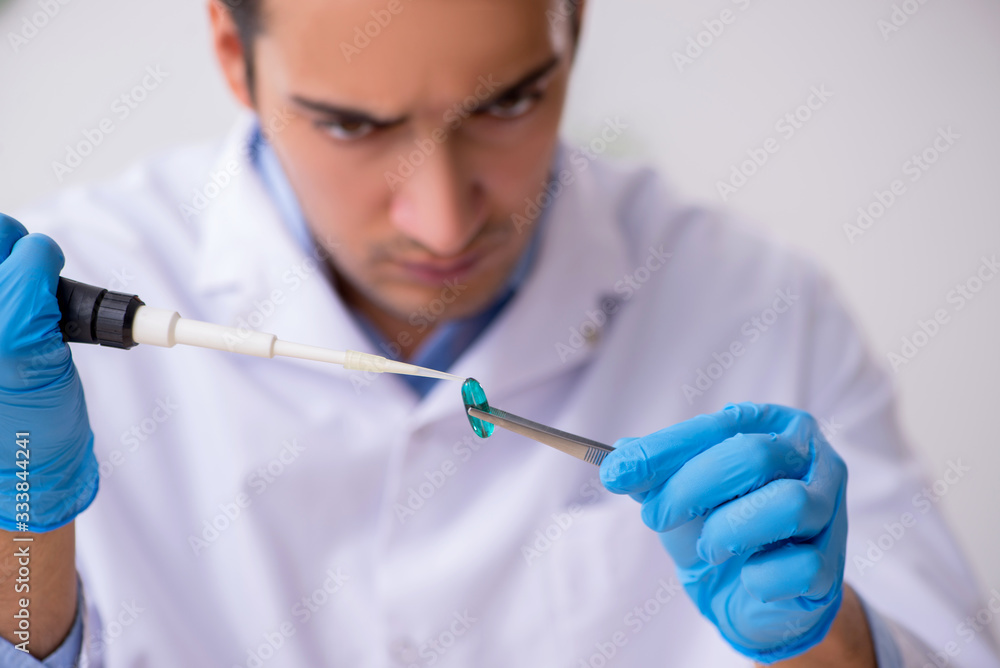 Young male lab assistant in drug synthesis concept Young male lab assistant in drug synthesis concept