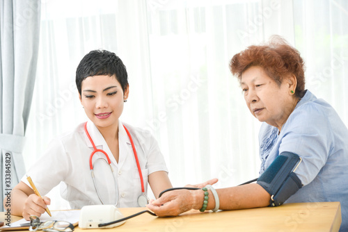 Asian doctor checking up her patient old woman in office.