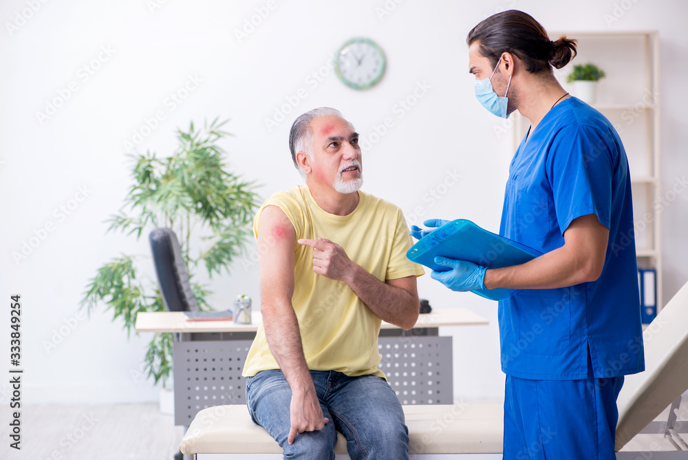 Fototapeta premium Injured old man visiting young male doctor traumatologist