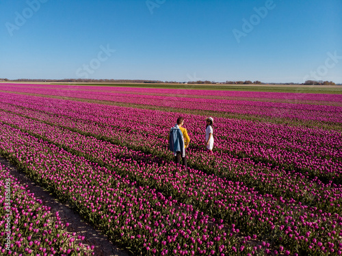 Photography Dutch tulip field, couple in flower field, woman with dress and summer hat in tu