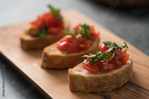 bruschetta with cherry tomatoes and spinach leaves on olive board