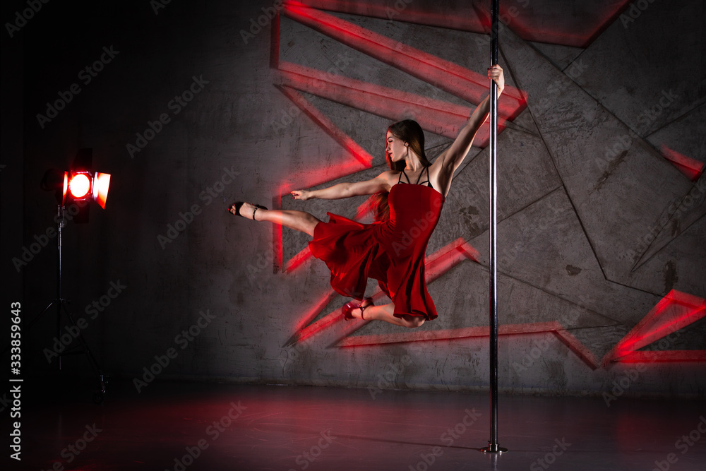Obraz premium Beautiful girl dancing on the pole at studio