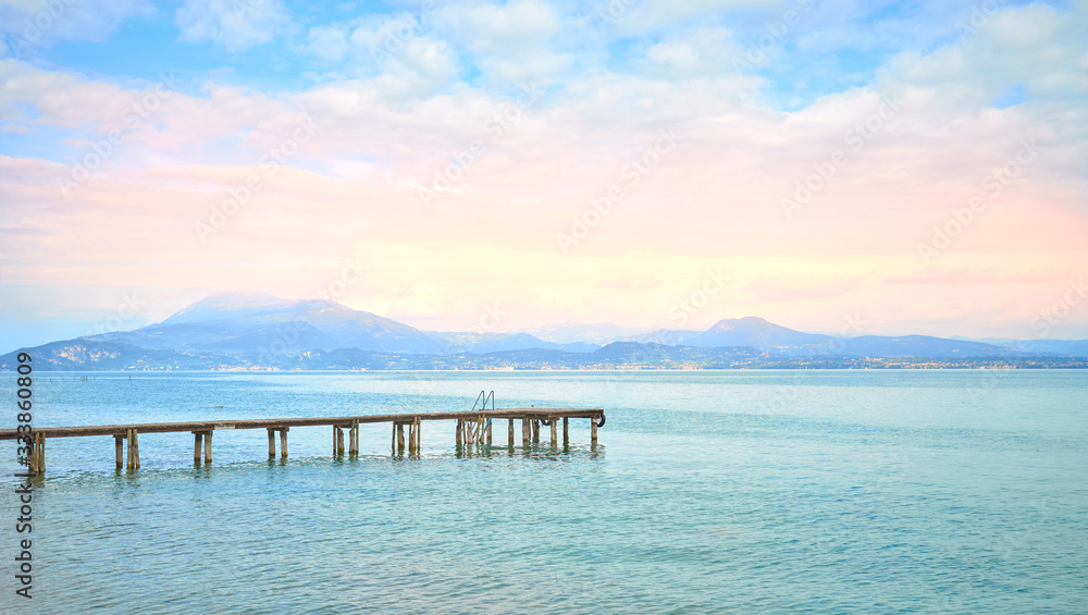 Wooden Pier at Lake Garda under dramatic Sky with beautiful light in the early mornung hours