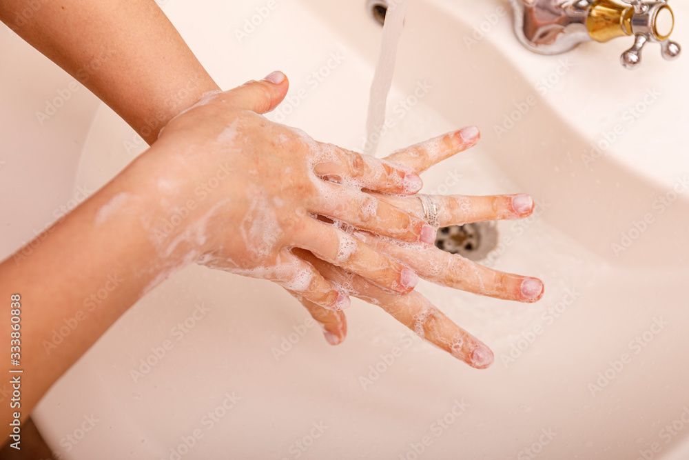 Young woman washing hands in modern sink with soap and lathering suds to protect against the coronavirus or covid 19. Bathroom hygiene concept. Young woman washing hands in modern sink with soap and lathering suds to protect against the coronavirus or covid 19. Bathroom hygiene concept.
