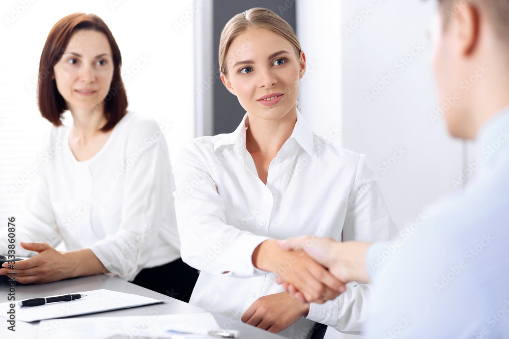 Business handshake by blonde woman and her partner at meeting. Concept of success and agreement