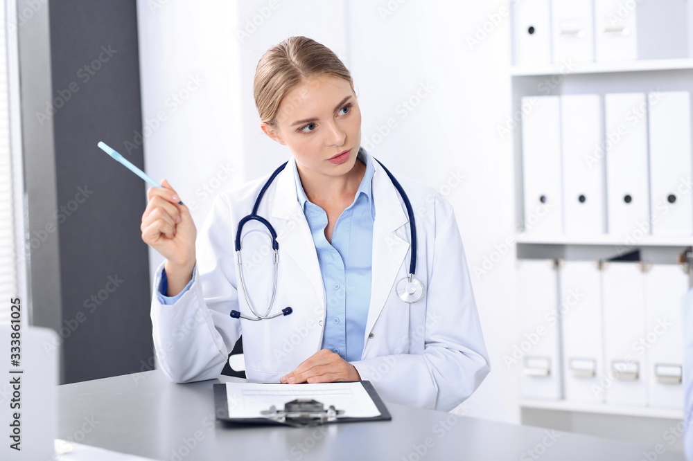Doctor and patient in clinic. Beautiful blonde physician consulting business man about his health. Medicine concept Doctor and patient in clinic. Beautiful blonde physician consulting business man about his health. Medicine concept