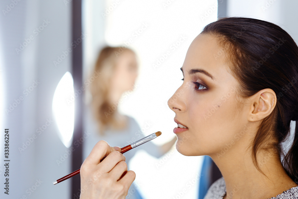 Professional makeup artist working with beautiful young woman. Bridal, fashion or nude style Professional makeup artist working with beautiful young woman. Bridal, fashion or nude style