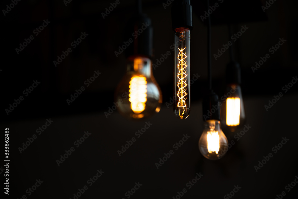 Bare bulb. Worm bokeh lights and dark background. Analog life. Vintage styled tungsten lamp in the darkness.