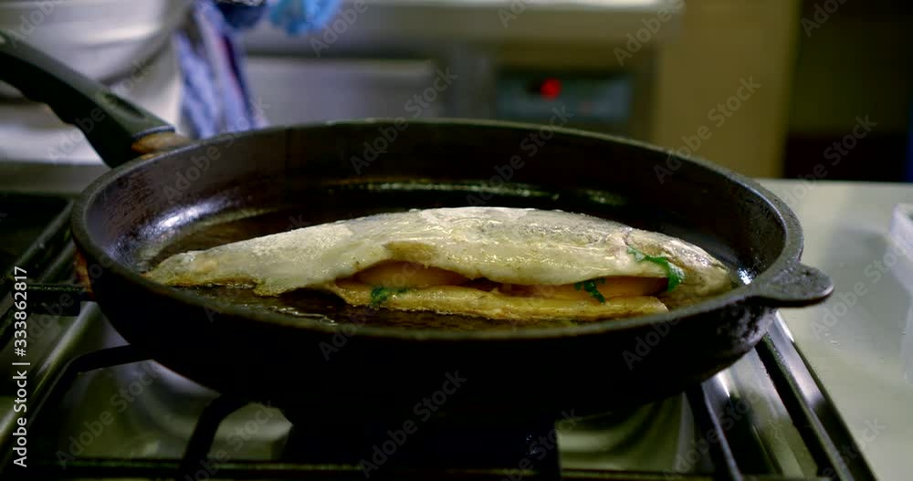 cooking of fish on kitchen, trout is roasting in oil at pan, cook is turning it cooking of fish on kitchen, trout is roasting in oil at pan, cook is turning it