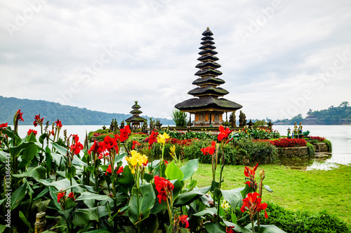 Pura Ulun Danu Bratan temple. Balinese landmark. Red and yellow flowers in the foreground. Bratan lake, Bali, Indonesia