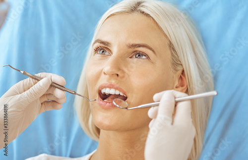 Smiling blonde woman examined by dentist at dental clinic. Healthy teeth and medicine concept