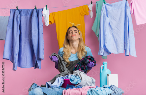 Fatigue woman looks away, stands near basket with pile of laundry
