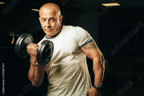 Fit senior man exercising with dumbbells in a gym