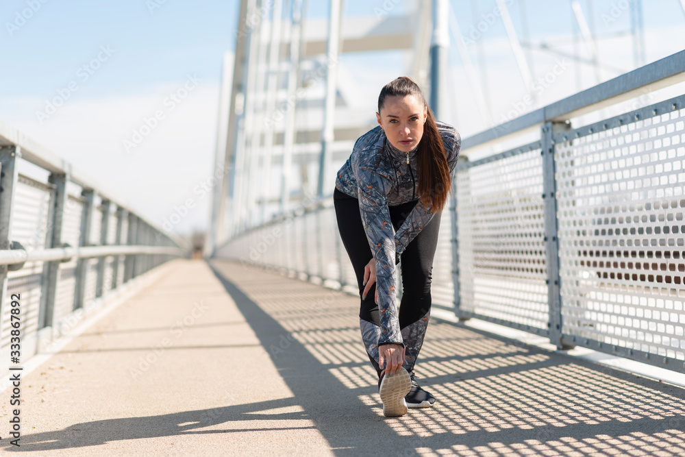 Young sporty woman doing stretching on bridge