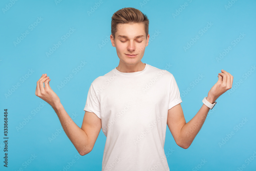 Relaxation, mind harmony. Portrait of man in casual white t-shirt holding arms in mudra gesture and meditating with peaceful expression, practicing yoga. indoor studio shot isolated on blue background Relaxation, mind harmony. Portrait of man in casual white t-shirt holding arms in mudra gesture and meditating with peaceful expression, practicing yoga. indoor studio shot isolated on blue background