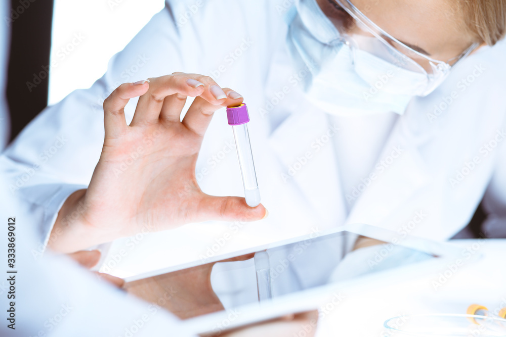 Coronavirus pandemic. Professional female scientist in protective eyeglasses researching tube in laboratory. Concepts of medicine and virus protection Coronavirus pandemic. Professional female scientist in protective eyeglasses researching tube in laboratory. Concepts of medicine and virus protection