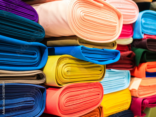 Rolls of bright multicolored fabric close-up. Coils of fabric are on the shelves in the store. Sample of coat cotton fabric in rolls photo