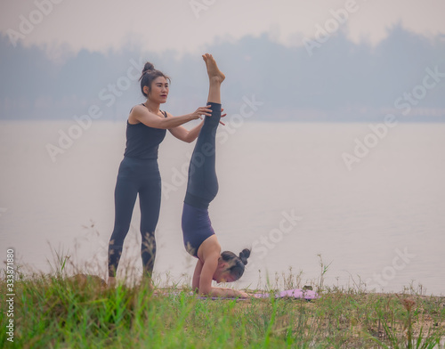 Fototapeta Naklejka Na Ścianę i Meble -  Cute and beautiful Asian women are practicing yoga by the lake.