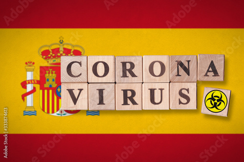 Spain flag background and wooden blocks with letters spelling CORONAVIRUS and quarantine symbol on it. Novel Coronavirus  2019-nCoV  concept for an outbreak occurs in Spain.