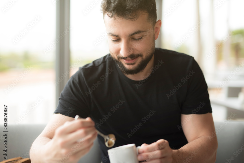 Bearded man stirs coffee in a restaurant Bearded man stirs coffee in a restaurant
