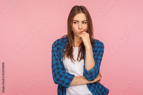 Φωτογραφία Portrait of thoughtful upset girl in checkered shirt pondering serious issues, looking with uncertain hesitant expression, making difficult choice