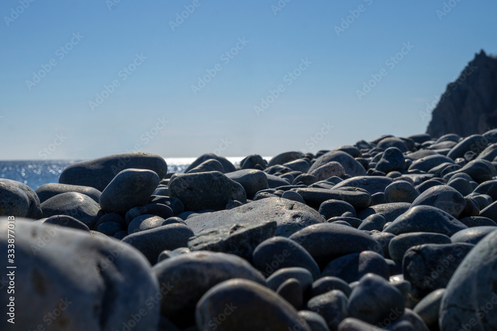 Obraz premium Pebble beach, large stones, sea and sky in the distance