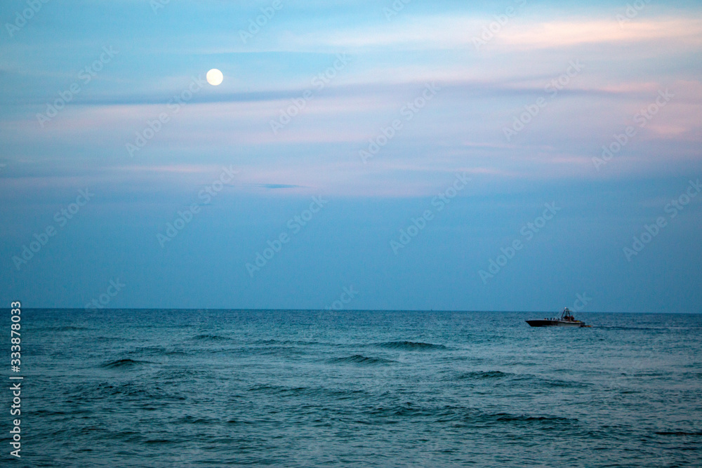 full moon in sunset evening sky over the ocean full moon in sunset evening sky over the ocean