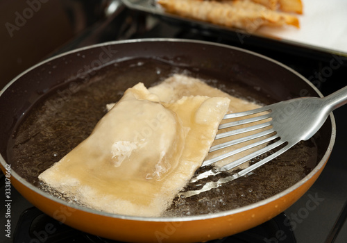 Wallpaper Mural Traditional Brazilian food called "PASTEL" - Put the "pastel" with a metal spatula in the frying pan with vegetable oil. Close-up. Top view. Horizontal shot. Torontodigital.ca
