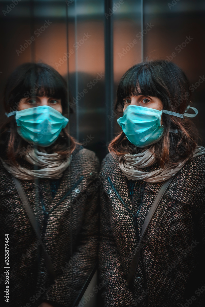 Health crisis, a sad young caucasian woman with a mask in a mirror of her home in the covid-19 quarantine Health crisis, a sad young caucasian woman with a mask in a mirror of her home in the covid-19 quarantine