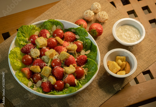 Caesar salad with strawberry on the wood table