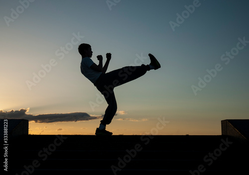 alone kung fu warrior is training against the sunset sky