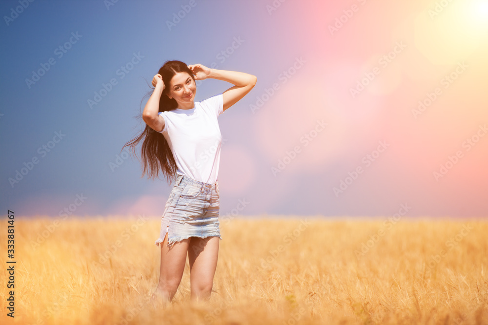 Happy fashion woman enjoying the life in the field. Nature beauty, blue sky and golden field with wheat. Outdoor lifestyle. Freedom concept. Woman in summer field of wheat