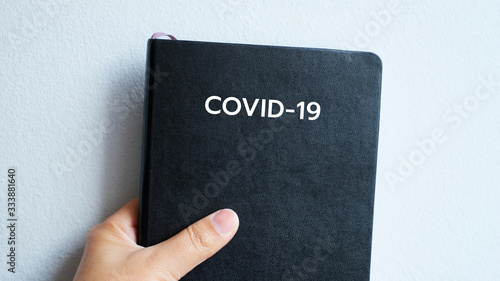 Text "COVID-19" on the black book cover with virus group images, coronavirus concept.
