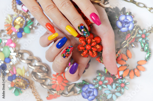 Creative bright saturated manicure on long nails with rhinestones.Nail art on women s hands on a white background with costume jewelry.