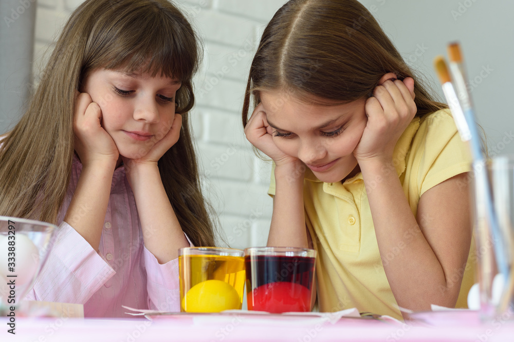Children look in glasses with liquid dye while egg staining Children look in glasses with liquid dye while egg staining