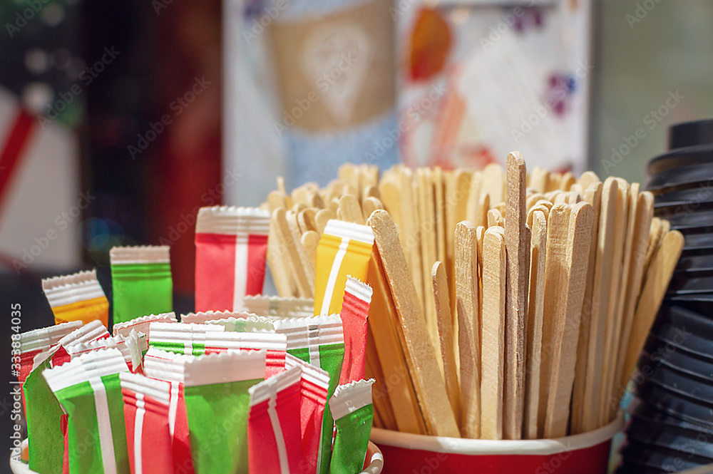 Fototapeta premium Glasses for coffee, sugar bags, lids close-up- Set for coffee machines. Selective focus, film grain