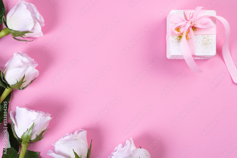 Pink rose and white gift box with pink ribbon on pink background