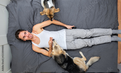 Man and dogs lying on bed with gray sheet