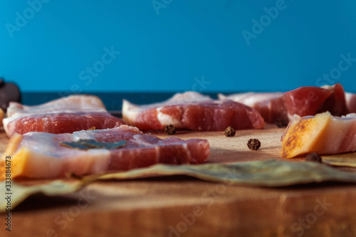 The meat, cut into portions, is laid on a wooden Board with spices, Bay leaves, black peas. Close up