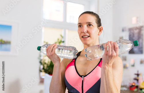 Frau macht Home Work out mit wasserflaschen als hanteln